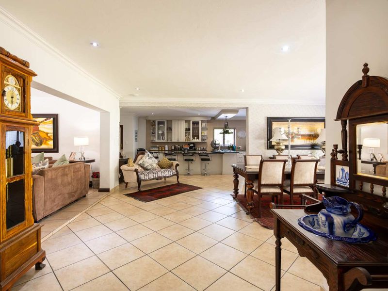 Spacious open-plan living area featuring tiled flooring, recessed lighting, and a functional kitchen with a breakfast bar, seamlessly connecting dining and lounge spaces.