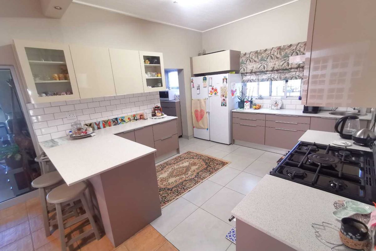 A functional kitchen featuring modern cabinetry, stone-look countertops, a gas hob, and a breakfast bar area with tiled flooring.