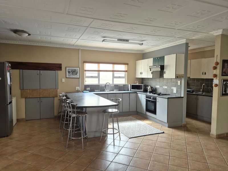 Spacious kitchen featuring a large island, built-in cabinetry, integrated oven and hob, tiled flooring, and a distinctive coffered ceiling design.