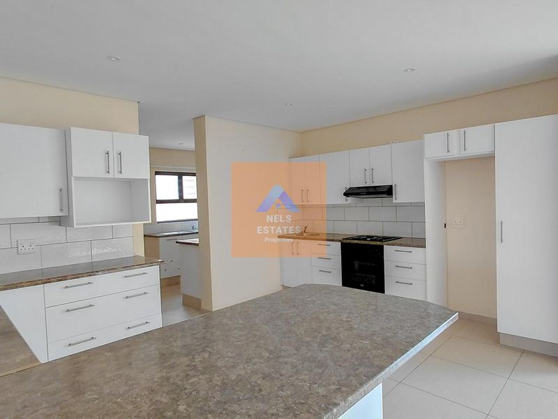 Modern kitchen featuring white cabinetry, laminate countertops, built-in oven, hob, extractor fan, and tiled backsplash, with an open-plan layout.