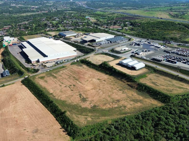 Aerial view of an industrial park featuring large warehouse facilities, extensive logistics yard space, and surrounding undeveloped land with direct road access.
