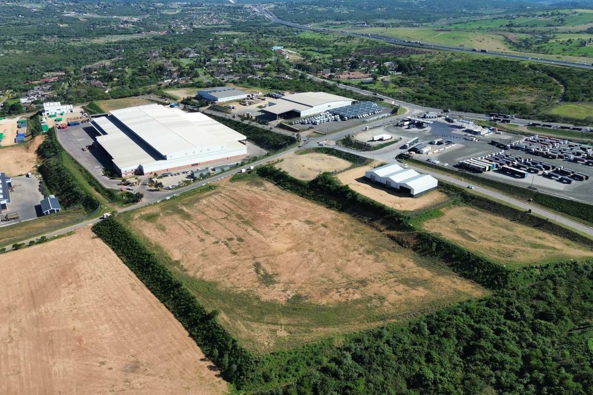 Aerial view of an industrial park featuring large warehouse facilities, extensive logistics yard space, and surrounding undeveloped land with direct road access.