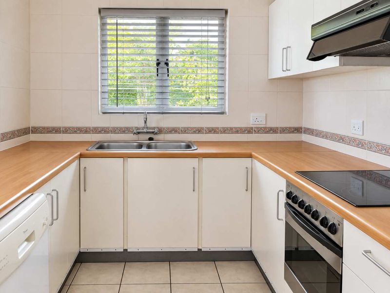 A functional U-shaped kitchen featuring laminate countertops, a double basin sink, built-in oven with electric hob, and tiled splashbacks.