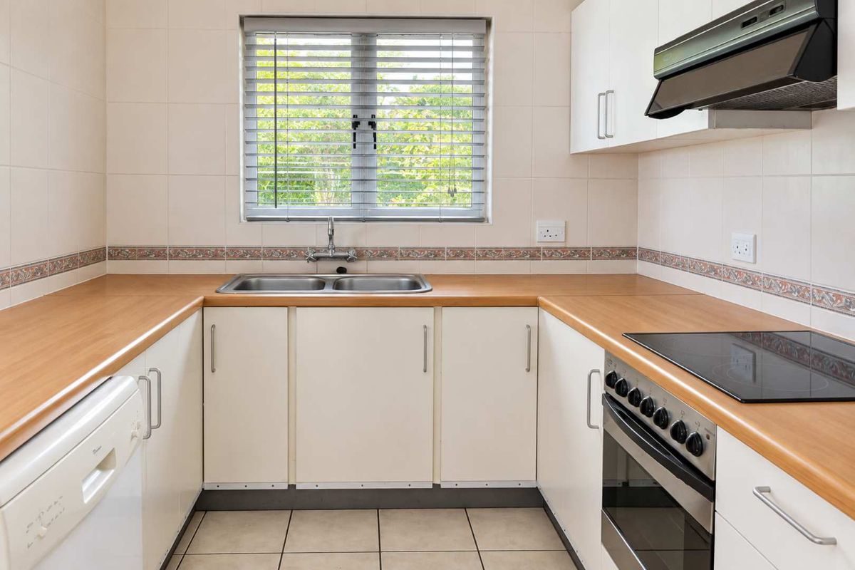 A functional U-shaped kitchen featuring laminate countertops, a double basin sink, built-in oven with electric hob, and tiled splashbacks.