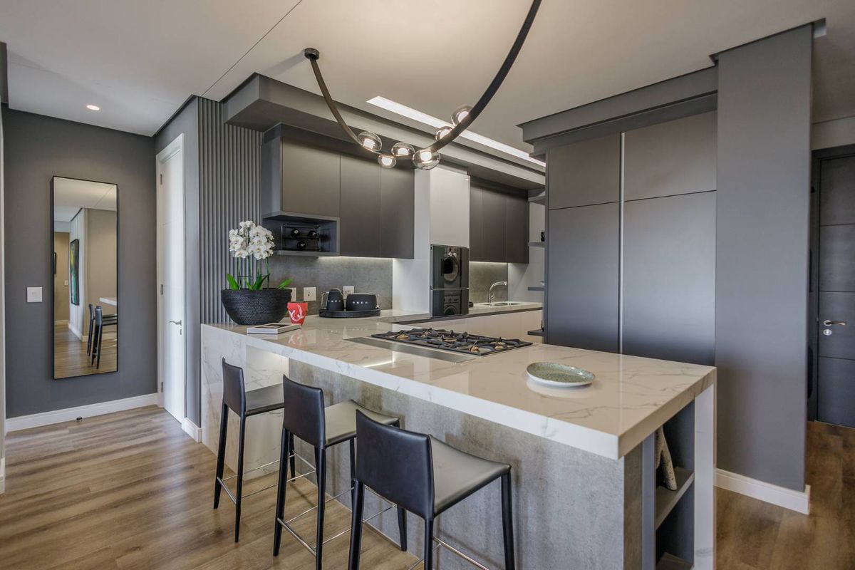 Modern kitchen featuring a marble-topped island with integrated gas hob, sleek dark cabinetry, and recessed lighting in an open-plan layout.