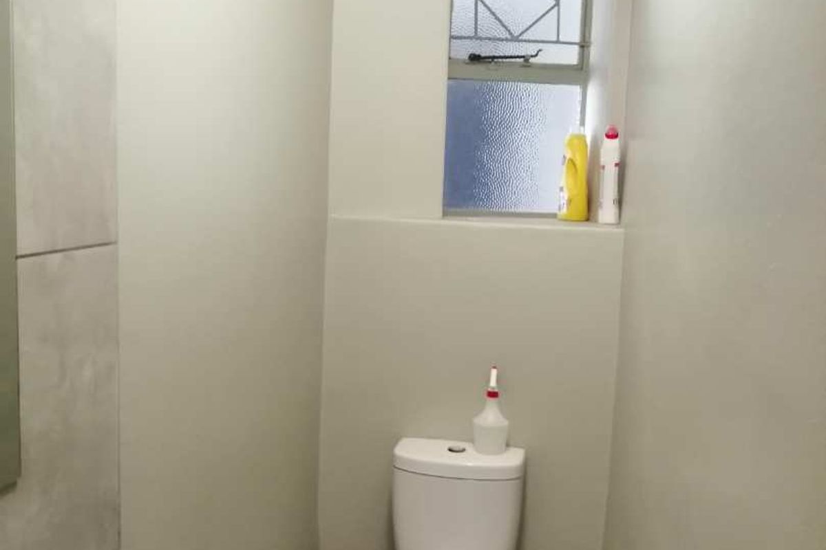 A compact bathroom featuring a toilet, bidet, and tiled finishes, providing essential functionality in a neutral setting.