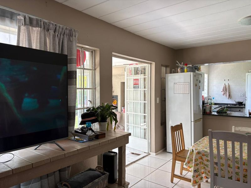 Open plan living and kitchen area featuring tiled floors, direct access to an outdoor patio, and functional kitchen cabinetry.