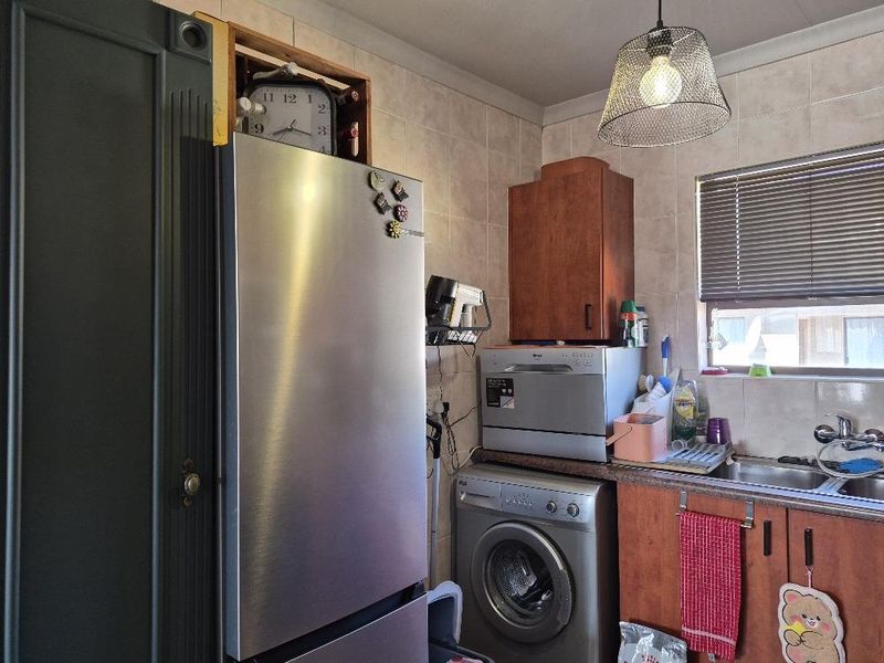 A functional kitchen area featuring built-in cabinetry, a stainless steel sink, and tiled backsplash, providing essential utility space for daily tasks.
