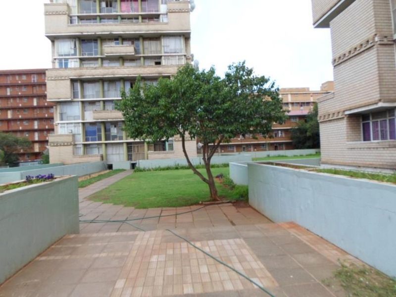 A communal outdoor area featuring a paved patio, a small lawn, and surrounding apartment building facades.