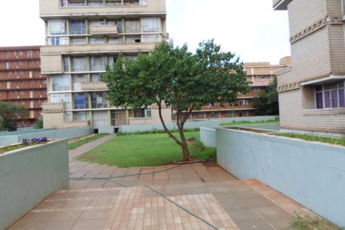 A communal outdoor area featuring a paved patio, a small lawn, and surrounding apartment building facades.