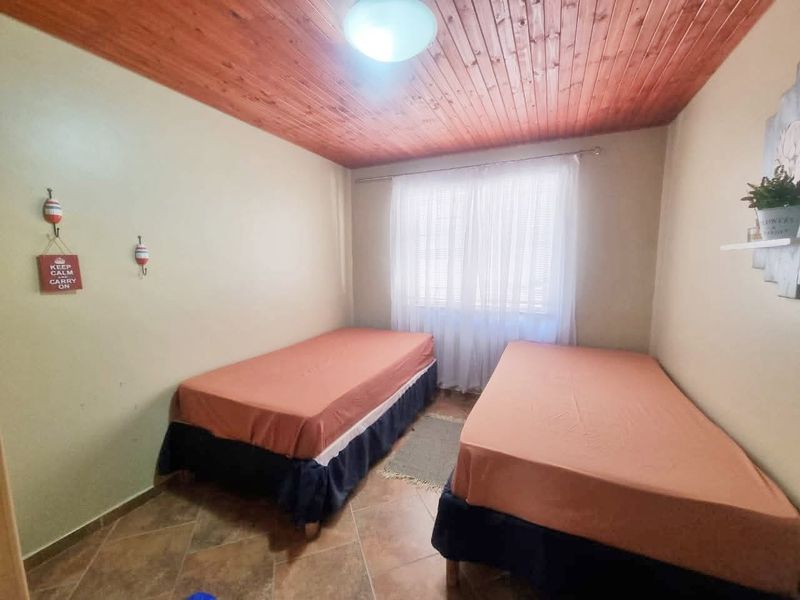 A bedroom featuring tiled flooring and a timber tongue and groove ceiling, providing a functional space with natural light.