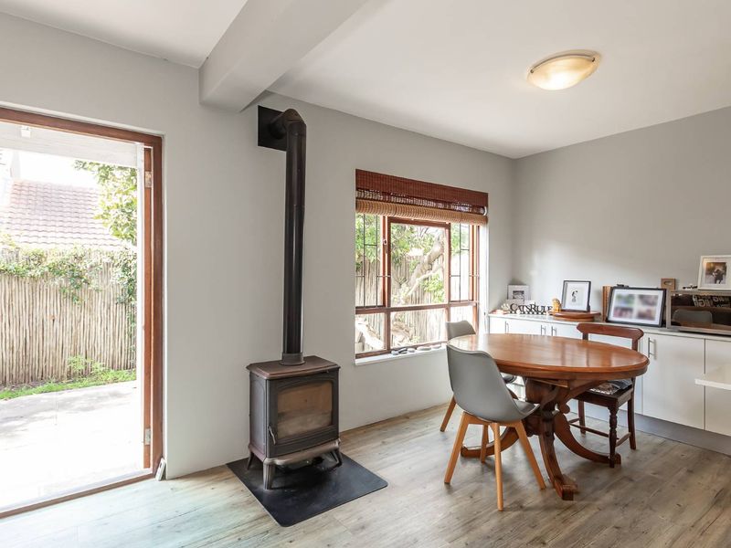 Open plan living area featuring a freestanding fireplace, laminate flooring, and direct access to the rear garden through a timber-framed door.