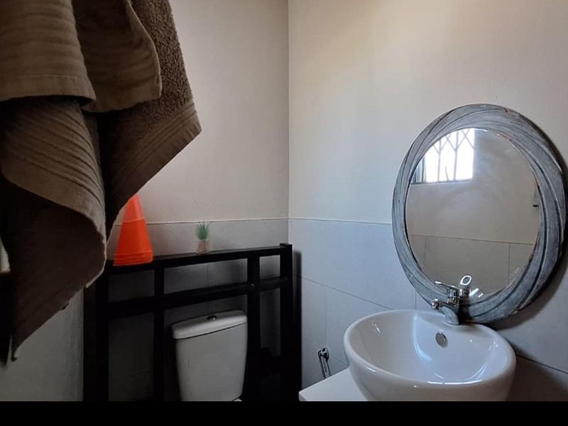 A compact bathroom featuring a modern ceramic basin with chrome mixer tap, a toilet, and tiled wall finishes.