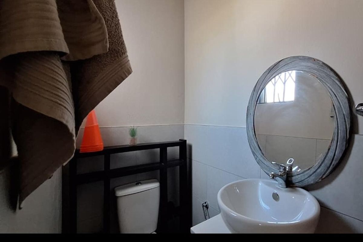 A compact bathroom featuring a modern ceramic basin with chrome mixer tap, a toilet, and tiled wall finishes.