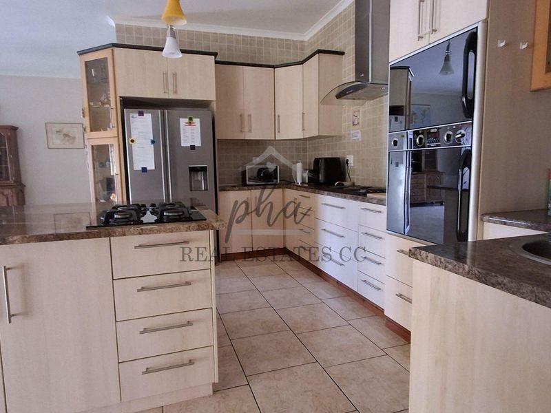 Functional kitchen featuring light wood cabinetry, granite countertops, built-in oven, gas hob, and tiled flooring with a neutral backsplash.