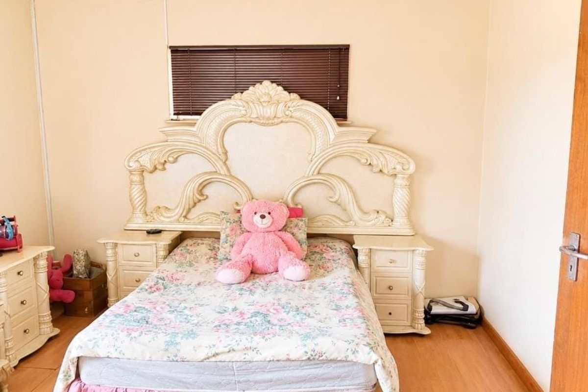 A bedroom featuring laminate flooring and venetian blinds, offering a neutral base for potential interior updates.