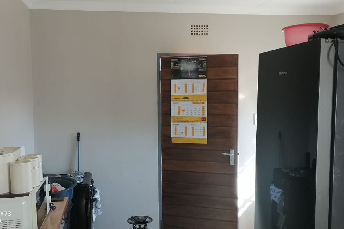 A functional kitchen area featuring a wooden door and ventilation, providing a practical space for daily household activities.
