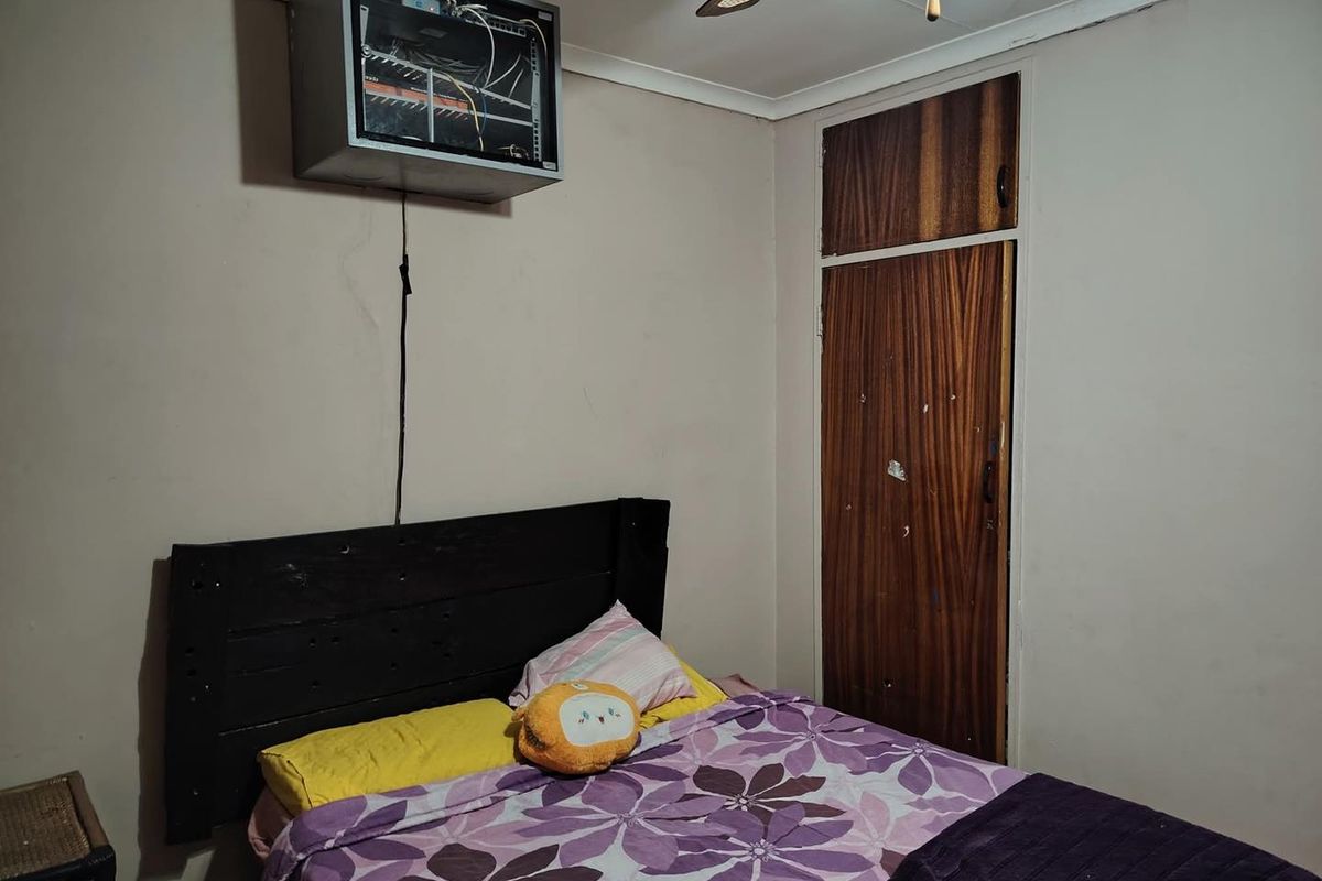 A bedroom featuring a built-in wooden cupboard and a wall-mounted network cabinet.