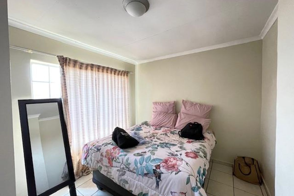 A compact bedroom featuring tiled flooring, a window with curtain tracks, and a ceiling-mounted light fixture.