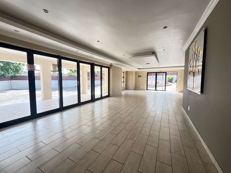 Spacious, open-plan living area featuring modern tiled flooring, recessed ceiling lighting, and large sliding glass doors providing seamless access to the outdoor patio.