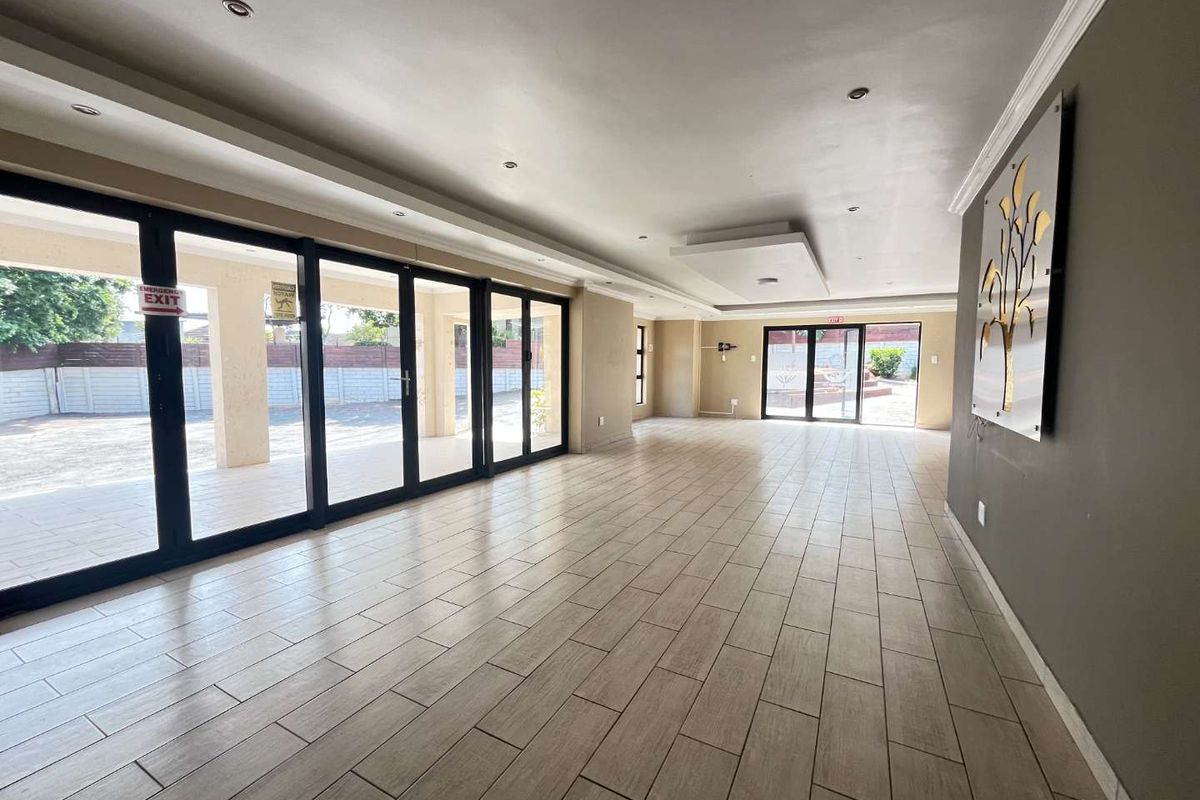 Spacious, open-plan living area featuring modern tiled flooring, recessed ceiling lighting, and large sliding glass doors providing seamless access to the outdoor patio.