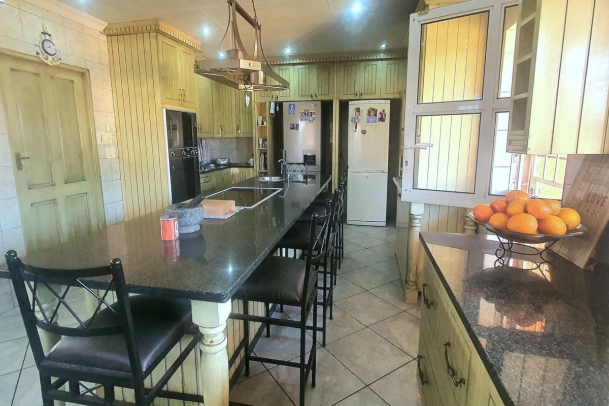 Spacious kitchen featuring a large central island with granite countertops, built-in oven, and extensive cabinetry storage.