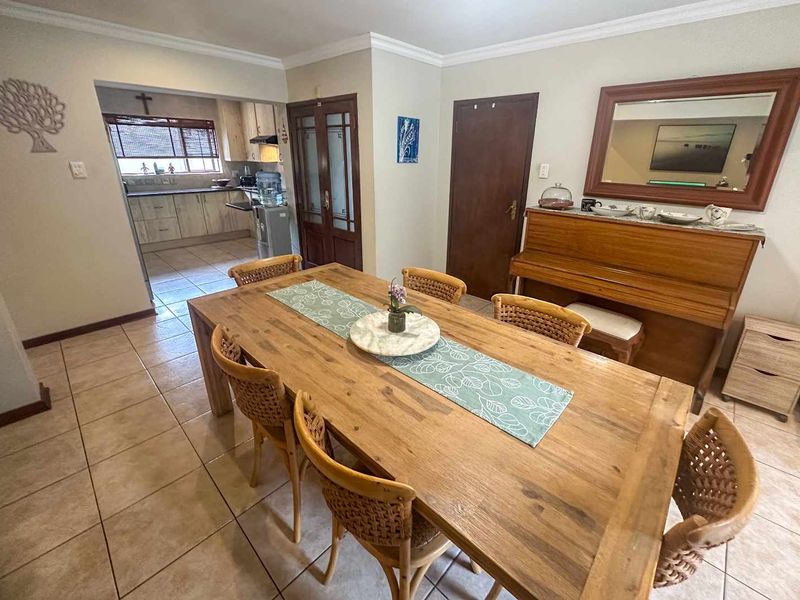 A dining room featuring tiled flooring and coved cornicing, with an open-plan transition into the adjacent kitchen area.