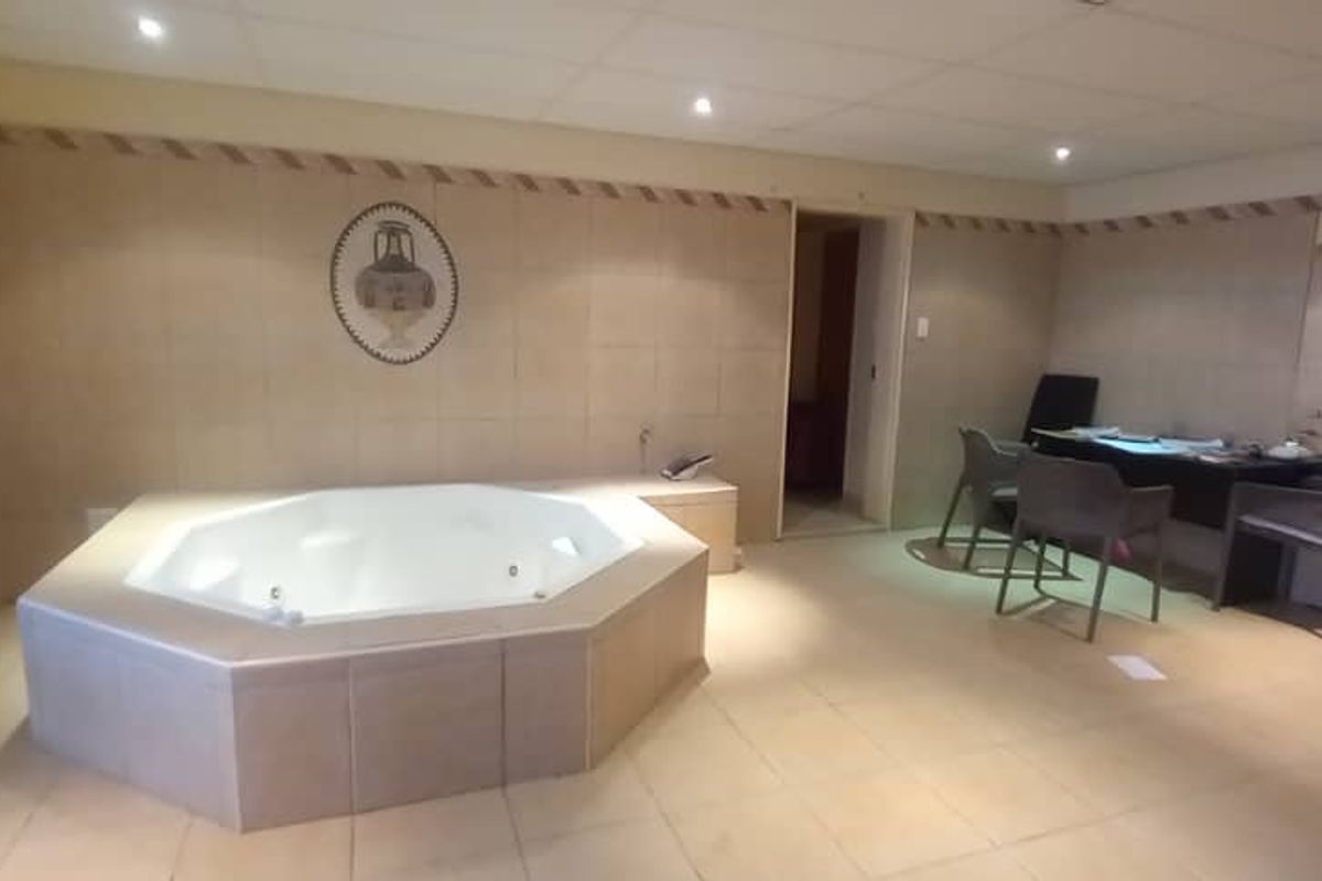A spacious bathroom featuring a built-in jacuzzi, tiled finishes, and recessed lighting, offering potential for a luxurious spa-like retreat.
