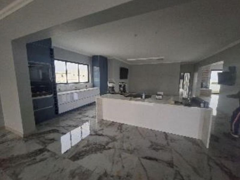 Spacious open-plan kitchen featuring a large central island, modern built-in cabinetry, and polished marble-look flooring throughout the living area.