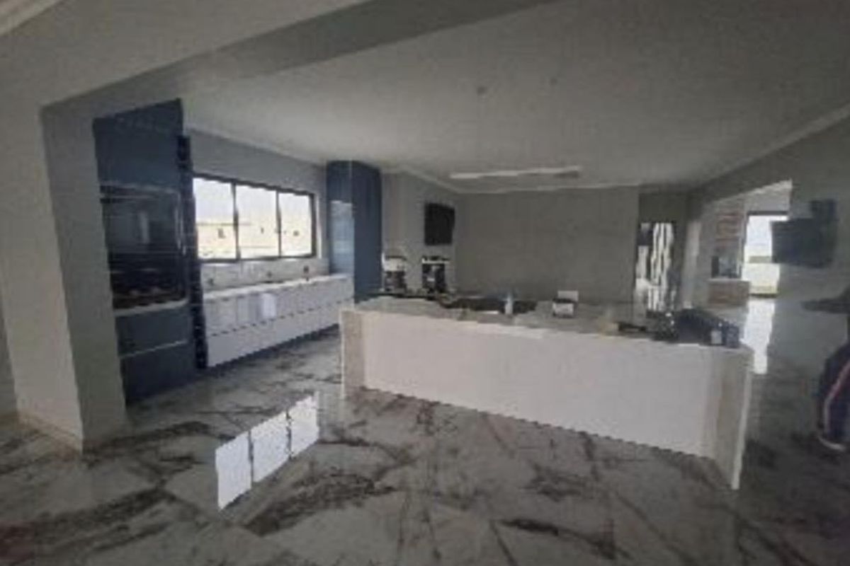 Spacious open-plan kitchen featuring a large central island, modern built-in cabinetry, and polished marble-look flooring throughout the living area.