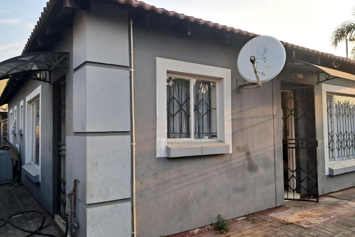 Exterior view of the property featuring a tiled roof, security gates, and satellite dish mounted on the side wall.