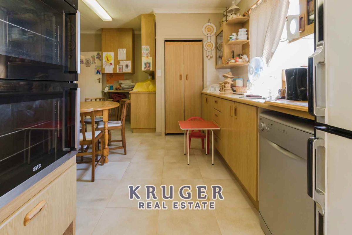 A functional kitchen featuring wood-look cabinetry, built-in double ovens, and tiled flooring, offering a practical layout with ample storage space.