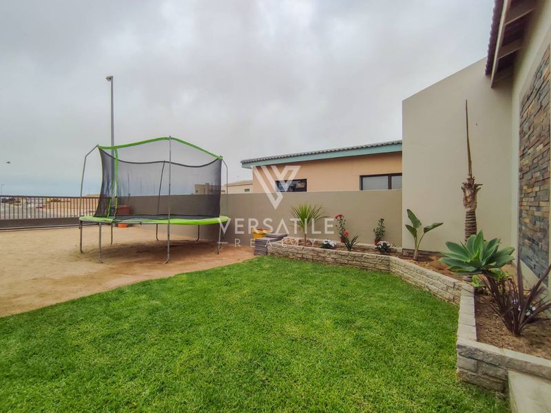 A rear garden area featuring a manicured lawn, stone-clad feature wall, and a low retaining wall, providing a clean outdoor space.