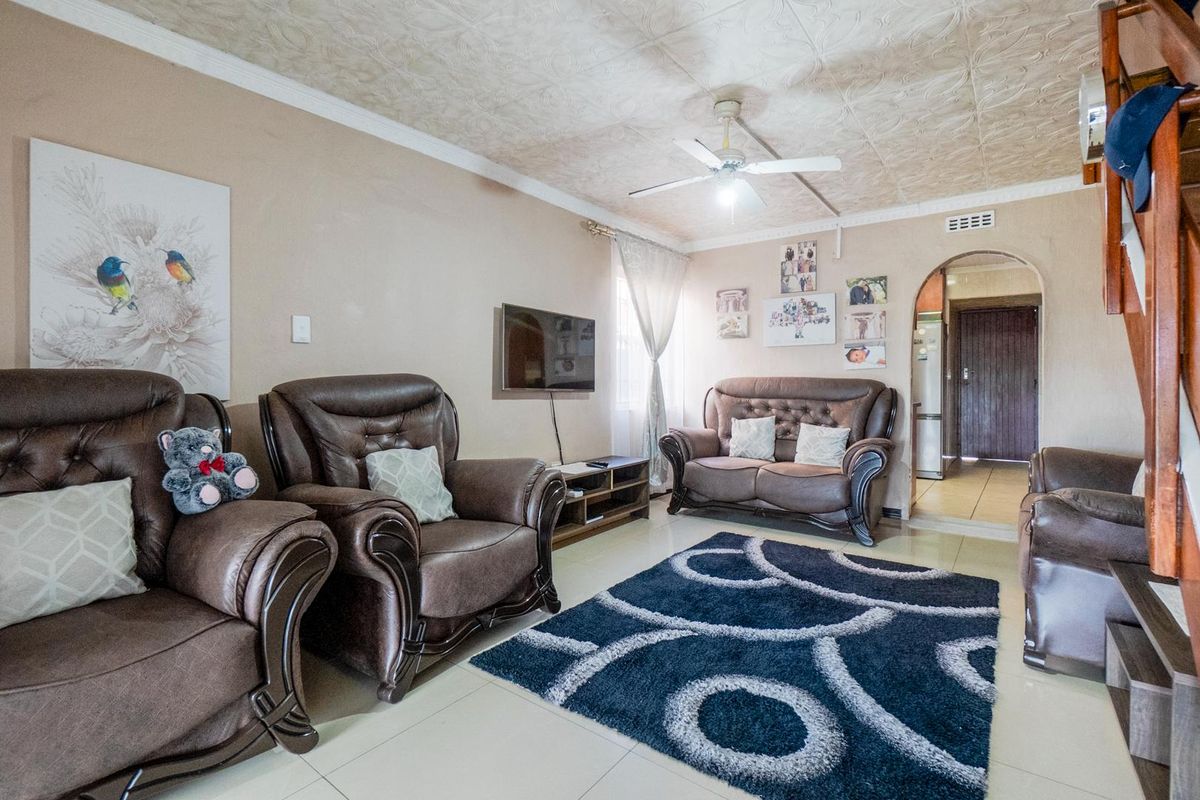 A living room featuring tiled flooring, a ceiling fan, and an arched doorway leading to an adjacent area.