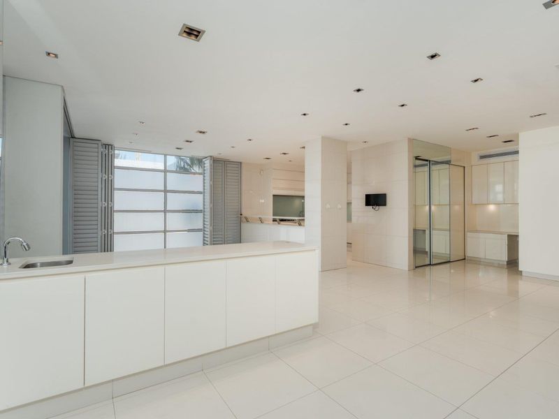 Spacious open-plan living area featuring a modern kitchen island, sleek built-in cabinetry, tiled flooring, and recessed lighting throughout.