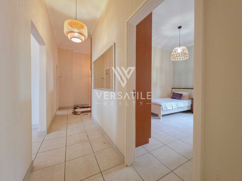 A bright, tiled hallway providing access to adjacent rooms, featuring neutral wall finishes and modern pendant lighting.