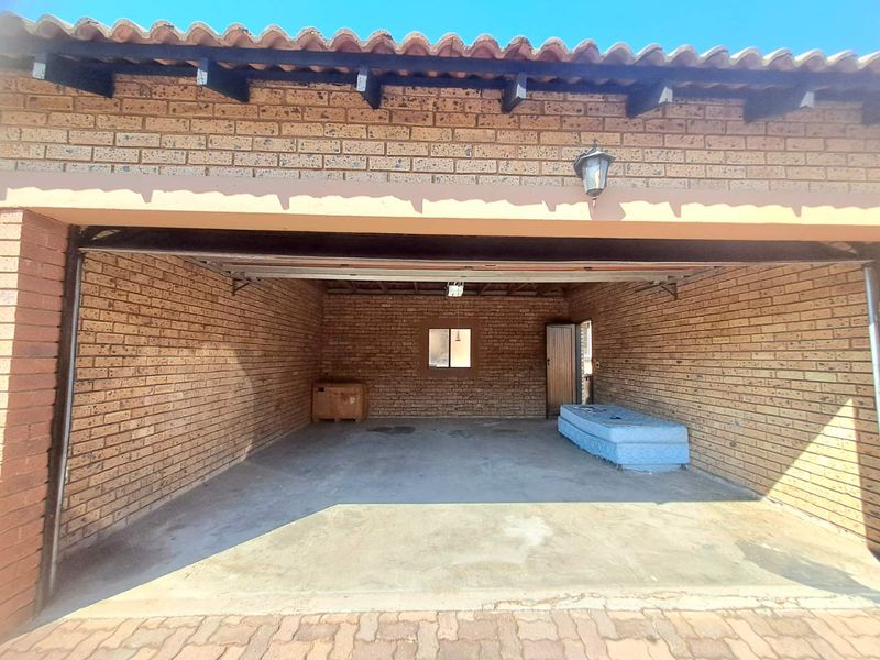 A spacious double garage featuring exposed brick walls, a concrete floor, and a tiled roof, providing secure parking or additional storage space.