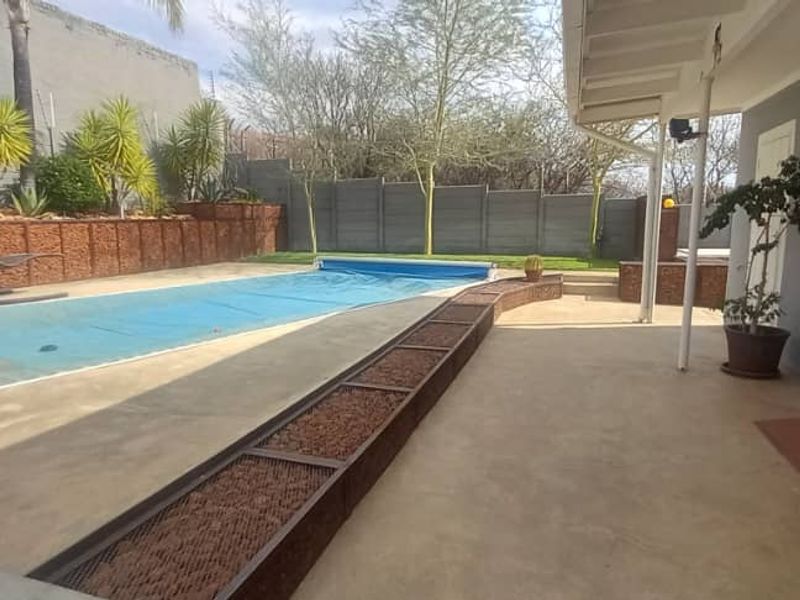 Outdoor pool area featuring a swimming pool with a cover, concrete patio space, and perimeter walling, providing a functional outdoor entertainment zone.