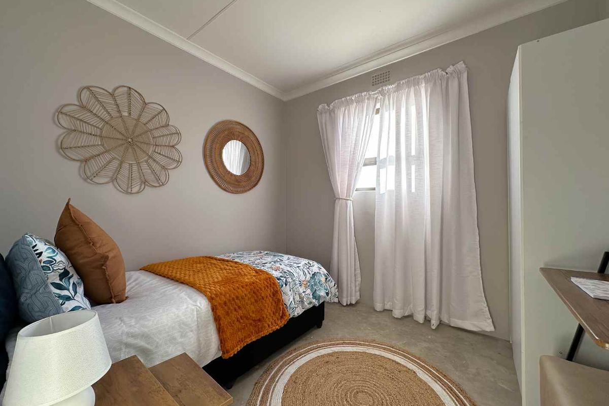 A well-maintained bedroom featuring neutral wall tones, a window with curtain treatments, and smooth flooring.