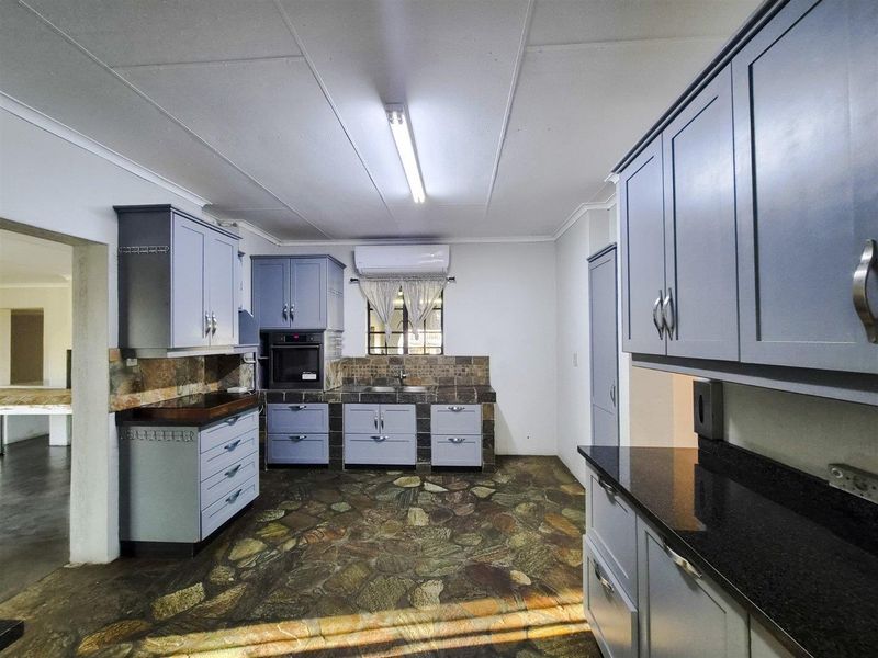 A functional kitchen featuring blue cabinetry, stone tile flooring, granite countertops, and a built-in oven, offering a solid foundation for modern updates.