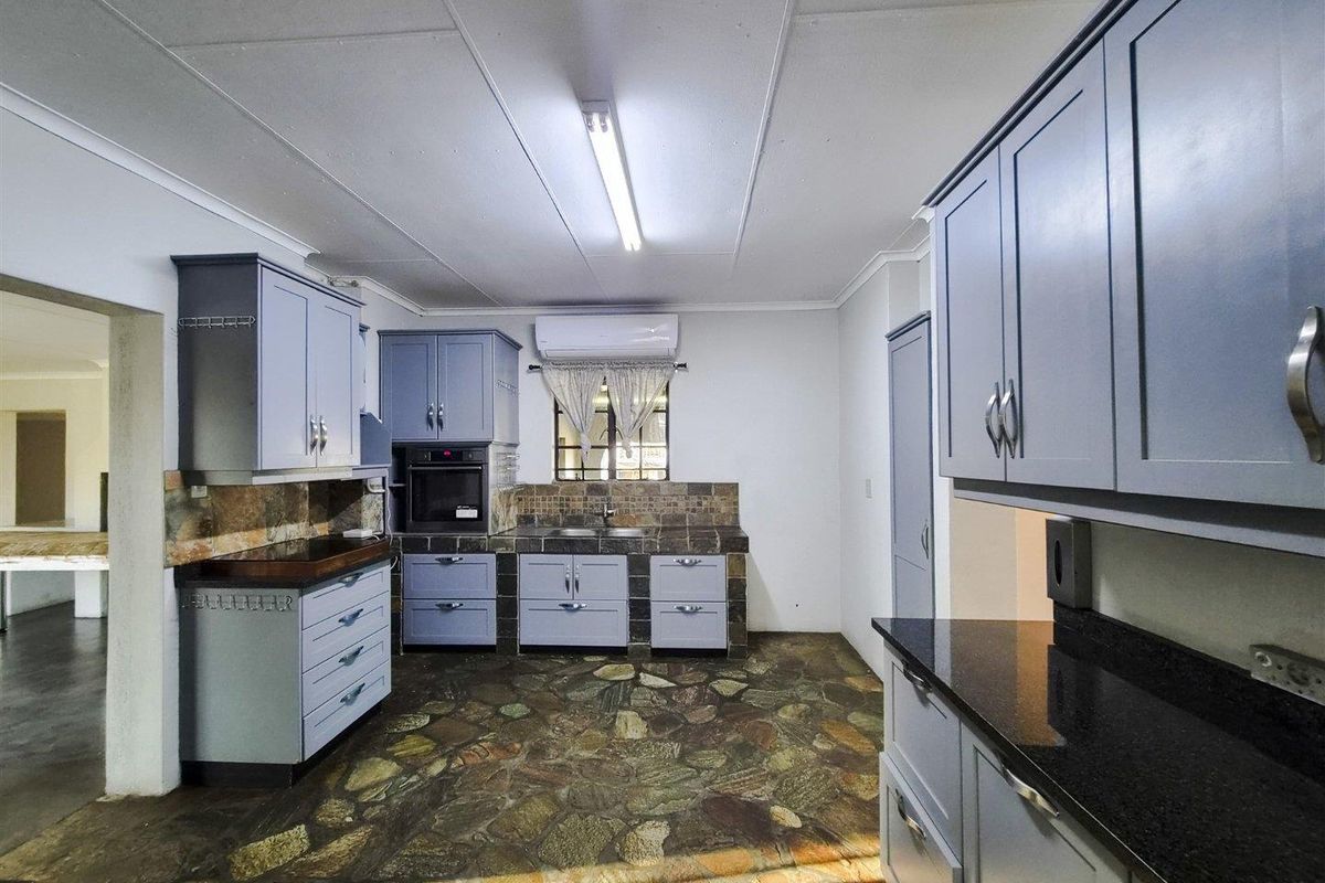 A functional kitchen featuring blue cabinetry, stone tile flooring, granite countertops, and a built-in oven, offering a solid foundation for modern updates.