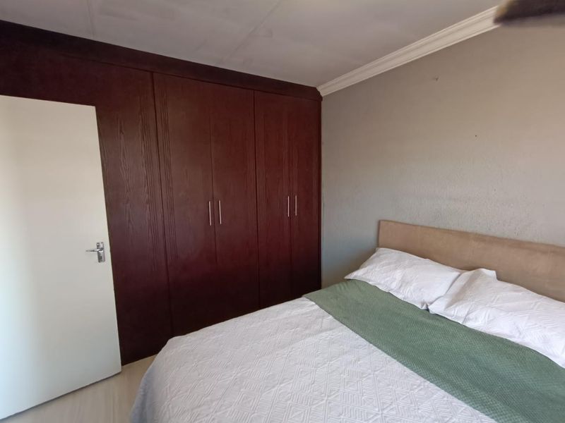 A bedroom featuring dark wood built-in cupboards and crown molding, with visible wall texture imperfections.