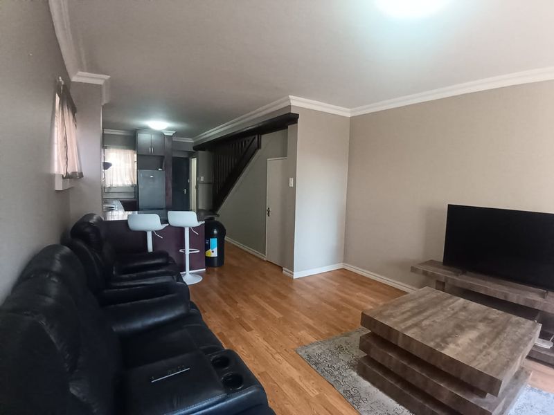 Open-plan living area featuring hardwood flooring, crown molding, and a breakfast counter connecting to the kitchen space.