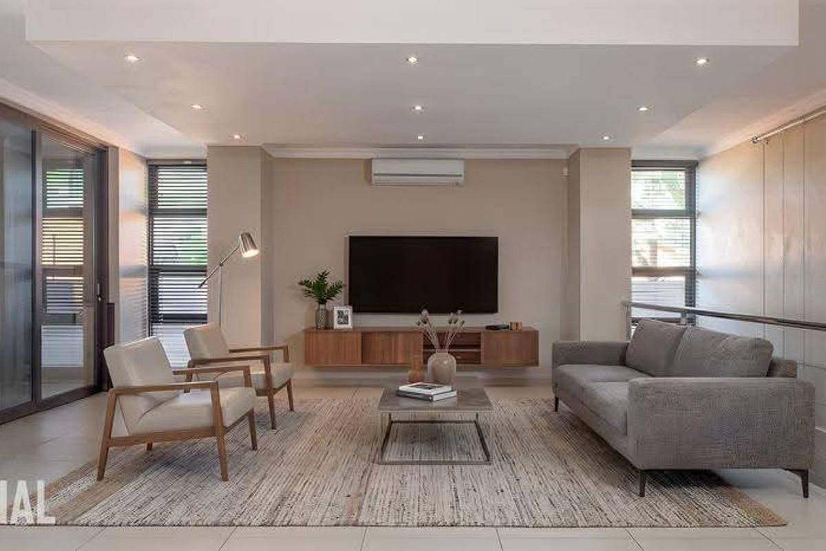 Modern open-plan living area featuring recessed ceiling lighting, large sliding glass doors, tiled flooring, and a sleek wall-mounted media console.