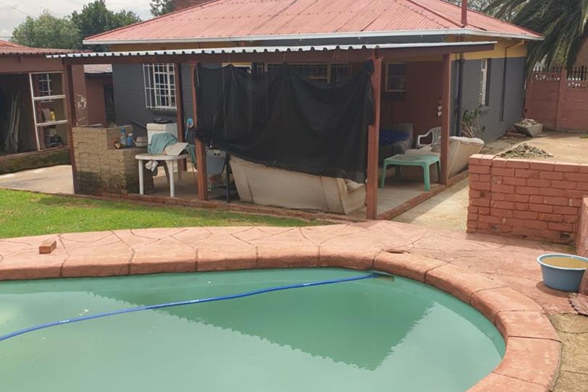 Rear view of the property featuring a swimming pool, a covered patio area, and a brick boundary wall.