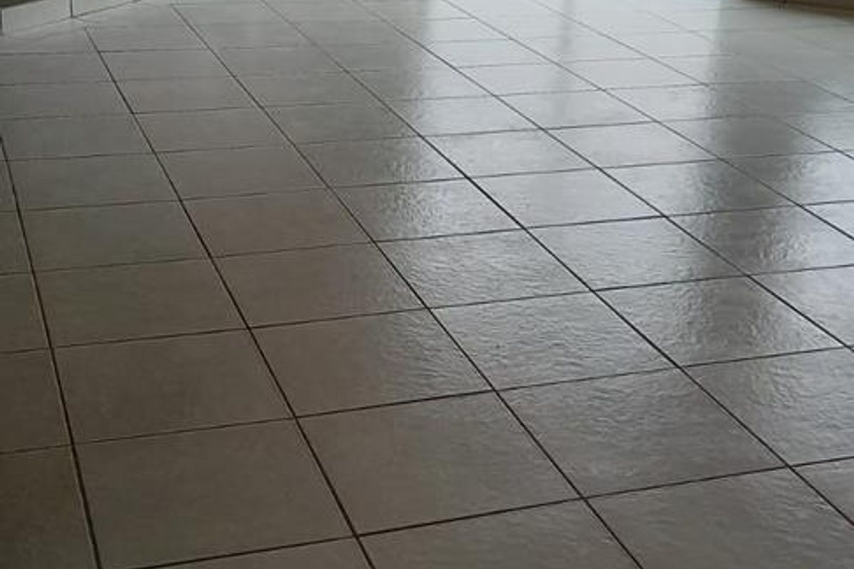 An empty living area featuring neutral tiled flooring and a sliding glass door providing access to the rear garden.