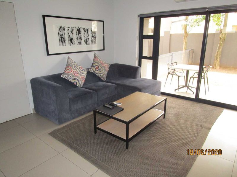 A well-maintained living room featuring tiled flooring, an air conditioning unit, and large sliding glass doors providing access to an outdoor patio area.