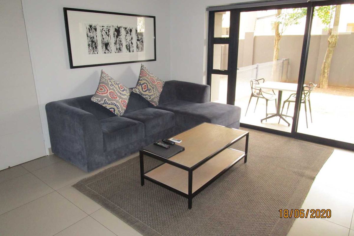 A well-maintained living room featuring tiled flooring, an air conditioning unit, and large sliding glass doors providing access to an outdoor patio area.