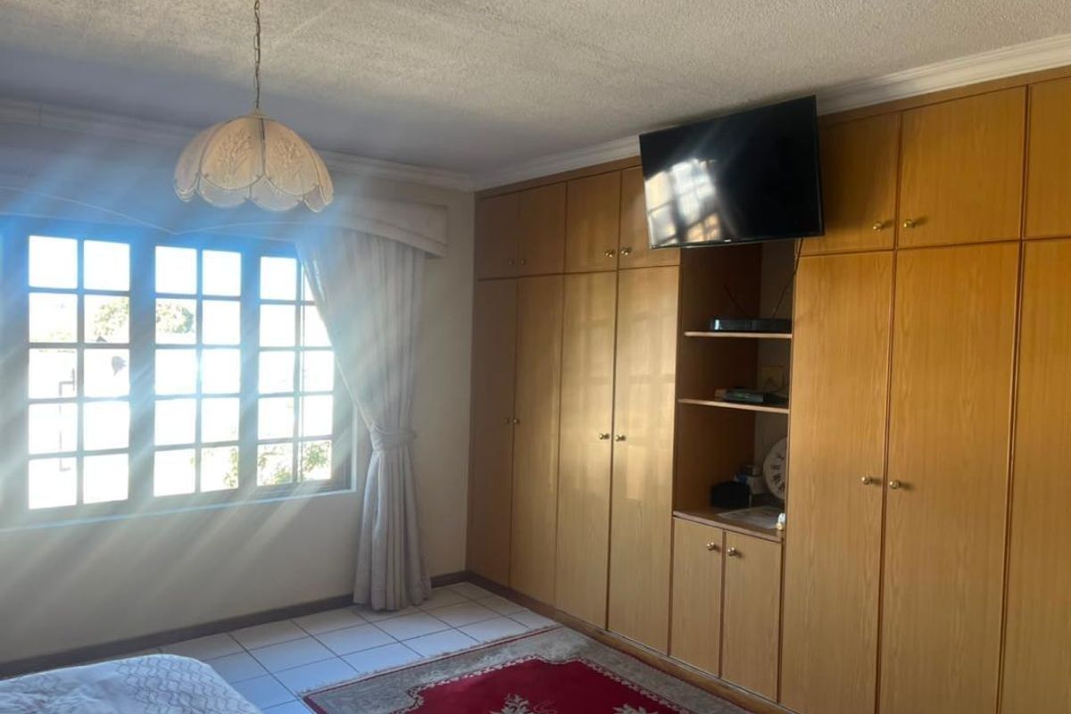 A bedroom featuring extensive built-in wooden cabinetry, tiled flooring, and a lattice window with natural light.