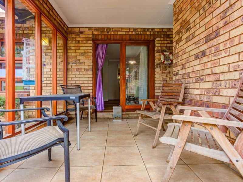 A covered patio area featuring face brick walls, tiled flooring, and large sliding glass doors providing access to the interior living space.